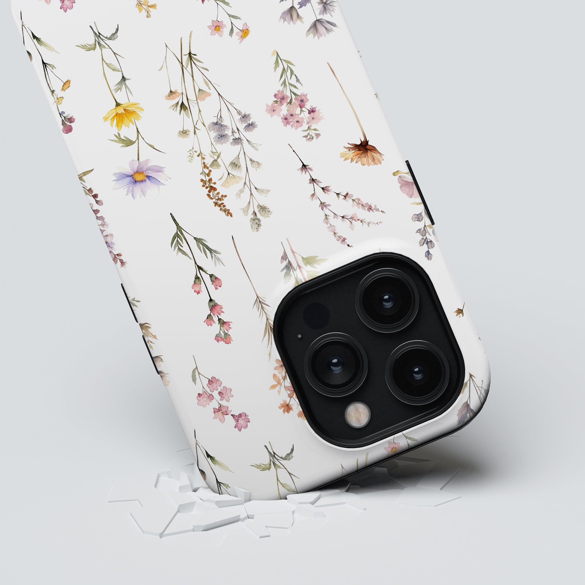 A Wild Flowers - Tough Case smartphone emerging through a cracked surface.