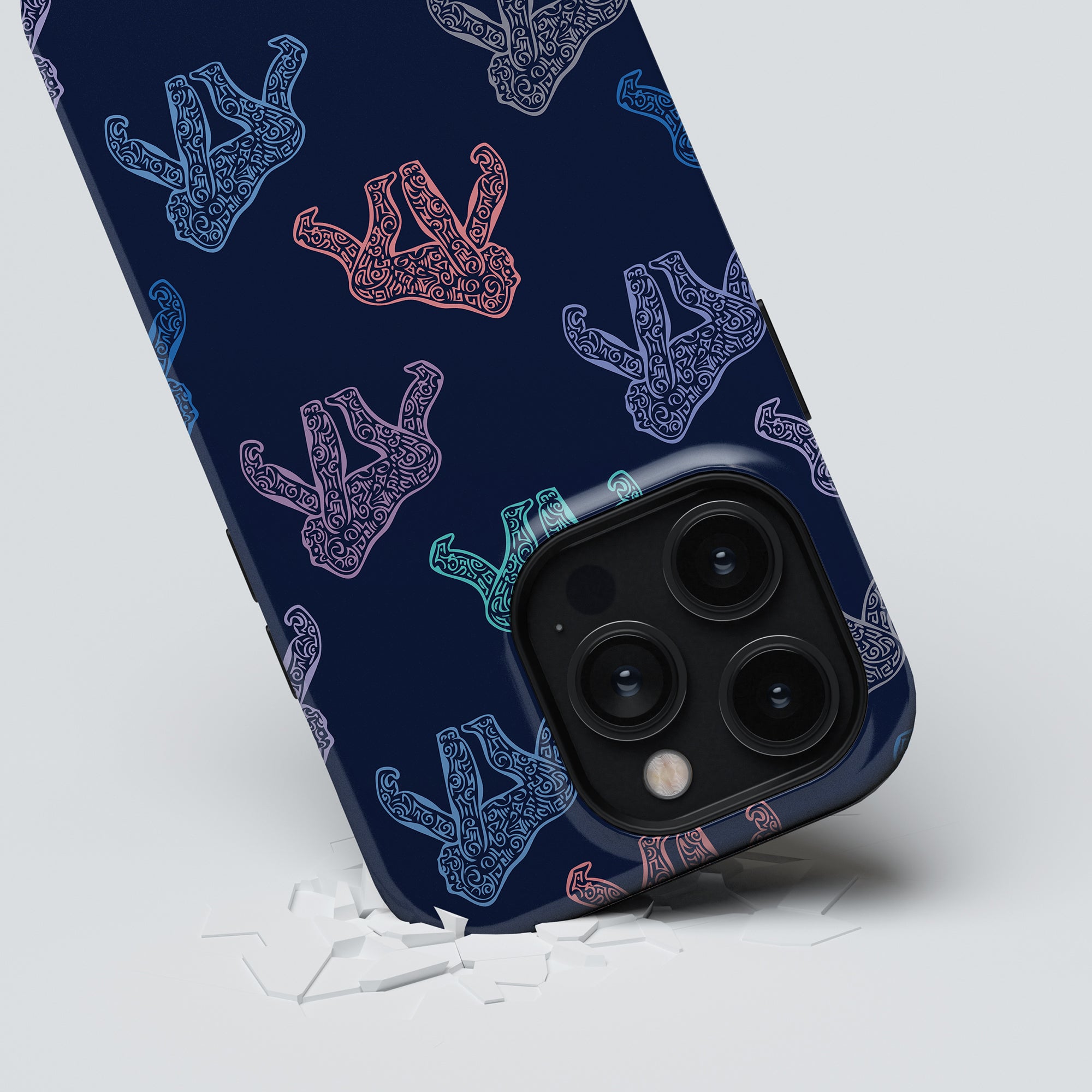 A smartphone with an Ancient Gorilla - Tough case, adorned with multiple outlined hands in various colors, rests on a cracked surface, revealing the phone's triple camera setup.