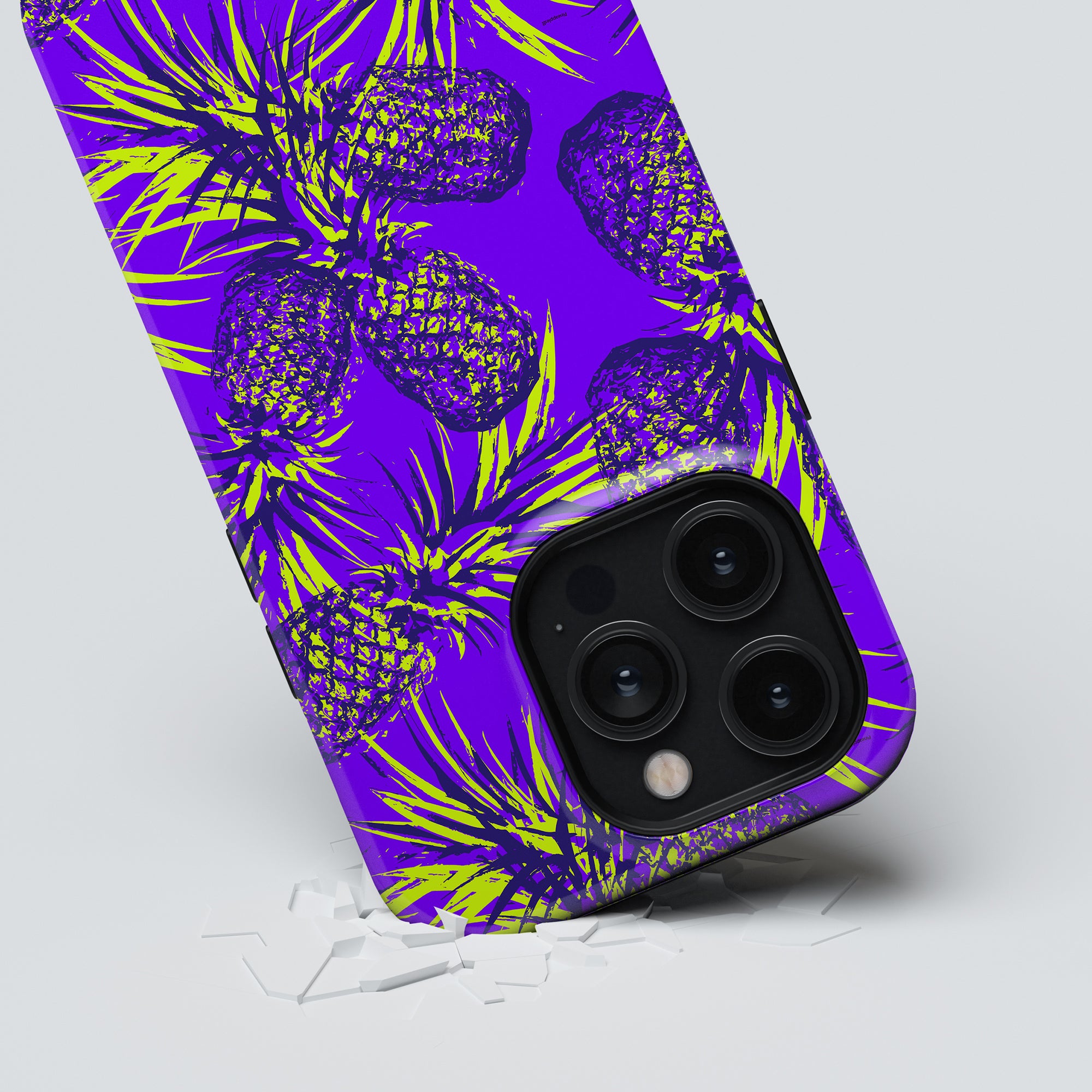 A smartphone with a vibrant purple and yellow Comosus-themed tough case emerging from a shattered glass surface.